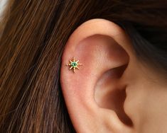 a close up of a person's ear with a green stone in the middle