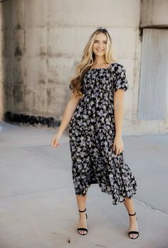 a woman wearing a black and white floral dress