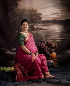 a woman in a pink and green sari sitting on a chair next to a painting