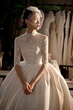 a woman wearing a wedding dress with a veil on her head, standing in front of mannequins