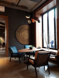 a dining room table and chairs in front of large windows with circular artwork on the wall