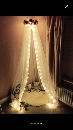 a canopy bed with lights on it and teddy bears in the corner next to it