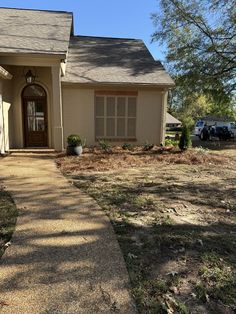 a house that is in the middle of a yard with grass and dirt on the ground