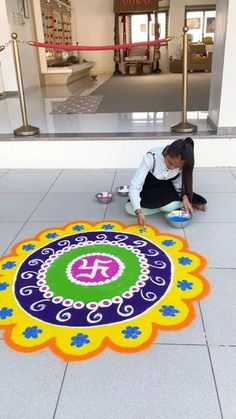 a woman kneeling down on the ground in front of a colorful rug