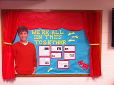 a bulletin board with pictures on it in front of a red curtain and drapes