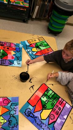 two young boys sitting on the floor working on their art project with paint and paper