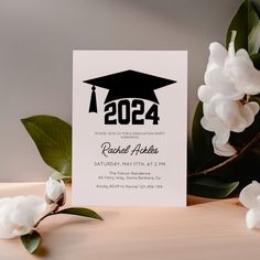 a graduation party card with the graduate cap on it next to white flowers and greenery