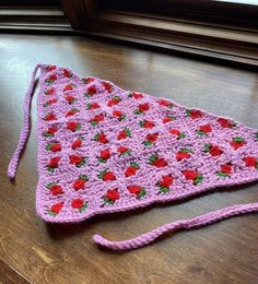 a pink crocheted bag sitting on top of a wooden table