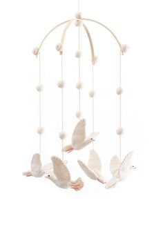 three white doves are flying in the air with balls hanging from it's sides