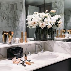 a bathroom with marble counter tops and white flowers