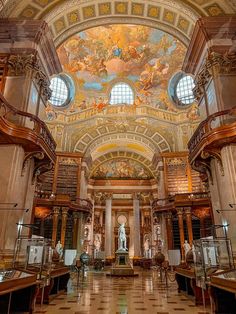 the inside of a library with many books on shelves and paintings on the ceiling above