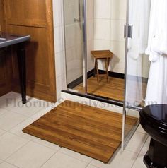 a bathroom with a stand up shower next to a sink and wooden flooring in front of a mirror