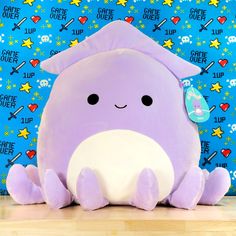 a purple stuffed animal sitting on top of a wooden floor next to a blue wall