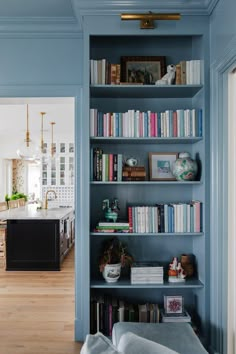 a blue bookcase with lots of books on it in the middle of a kitchen