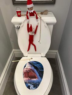 the elf is on top of the toilet with his mouth open and teeth wide open