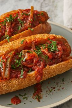 two hot dogs on buns covered in marinara sauce