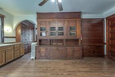 an empty kitchen with wooden cabinets and wood flooring, along with a ceiling fan