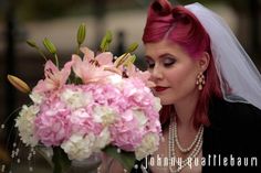 a woman with red hair is holding a bouquet of pink and white flowers in front of her face