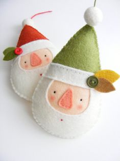 two felt santa claus ornaments on a white surface