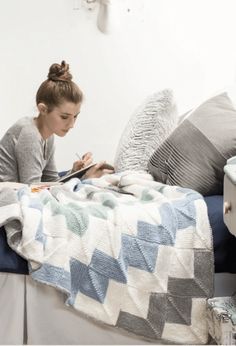 a woman sitting on a bed reading a book