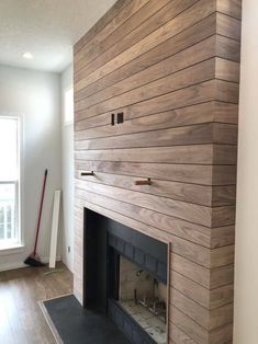 an empty room with a fireplace and wood paneling on the wall, along with hard wood flooring