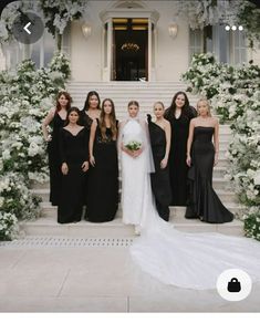 a group of women standing next to each other in front of a building with white flowers