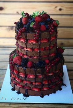 a triple layer chocolate cake with strawberries and berries on top