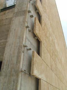 the side of a building that is made out of concrete and has metal brackets attached to it