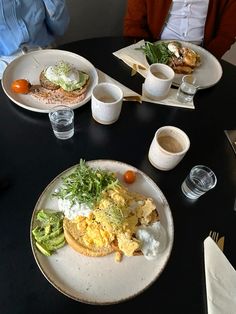 two people sitting at a table with plates of food and drinks in front of them