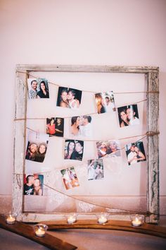 an old frame with photos hanging from it and candles on the floor next to it