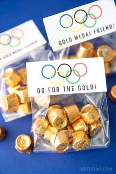 gold foiled candy bags with the olympic logo on them, sitting in front of some herspooos