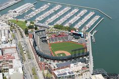 an aerial view of a baseball stadium with boats docked in the water and buildings around it