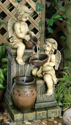 two cherubs sitting on top of a fountain with water pouring out of it