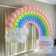 a rainbow balloon arch with balloons hanging from it