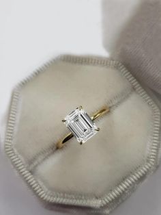 an emerald cut diamond ring sits in a velvet case