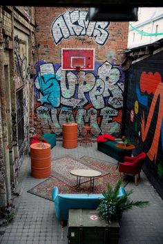 an alleyway with graffiti on the walls and tables, couches, and chairs