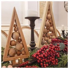 three wooden christmas trees on display in front of a candle holder and other decorations with candles