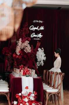 a woman sitting at a table with red and white flowers