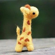 a small toy giraffe sitting on top of a wooden table