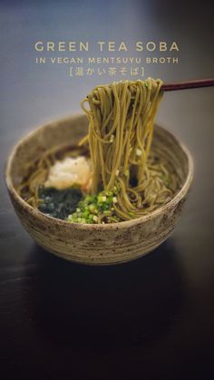 a wooden bowl filled with noodles and vegetables next to chopsticks on a table