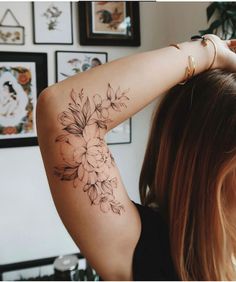 a woman with a flower tattoo on her left arm and right arm behind her head