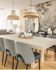 a dining room table with chairs and a large mirror on the wall above it,