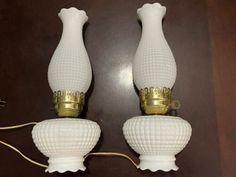 two white glass lamps with gold trim on the top and bottom one is turned off