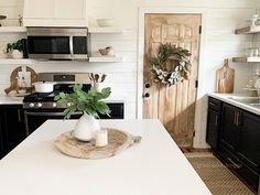 a kitchen with black cabinets and white counter tops, an open door leading to the dining room