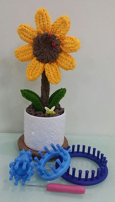 a crocheted flower sits in a pot next to scissors