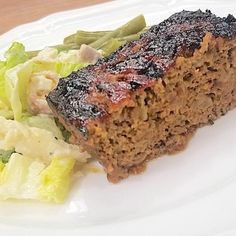 a piece of meatloaf on a white plate with lettuce