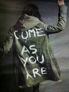 a woman with a jacket that says come as you are written on the back of her coat