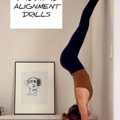 a woman is doing a handstand on her head while holding onto the wall