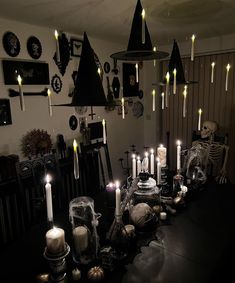 a table topped with lots of candles next to a wall filled with skulls and skeletons