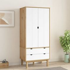 a white and wood cabinet with drawers in a room next to a potted plant